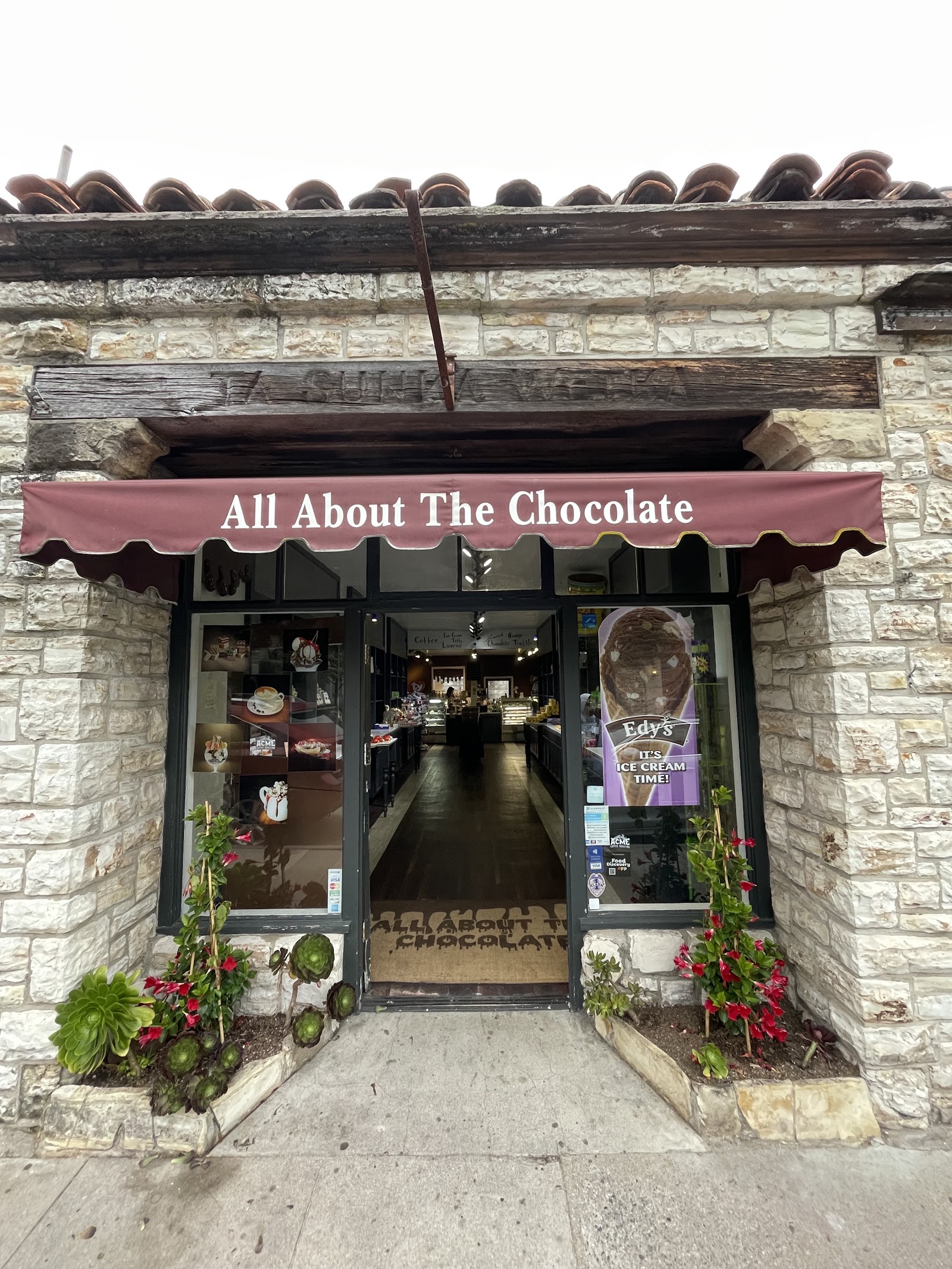 The burgundy-awning storefront of All About the Chocolate on Dolores Street